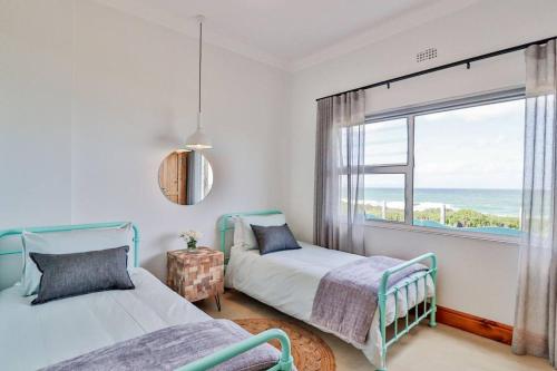 a bedroom with two beds and a window with the ocean at 78 Beach Road - Seafront luxury bliss in Kleinmond