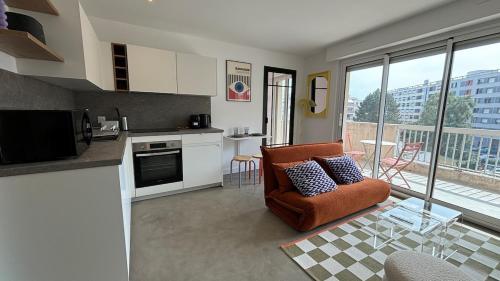une cuisine avec une chaise orange et un salon dans l'établissement Le BAUHAUS appart moderne et rénové avec parking, à Annemasse