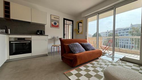 Il comprend un salon avec une chaise orange et une cuisine. dans l'établissement Le BAUHAUS appart moderne et rénové avec parking, à Annemasse