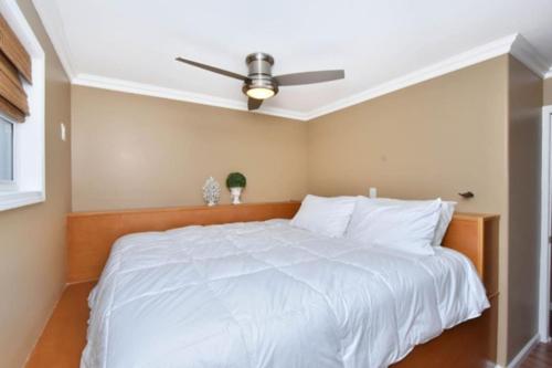 a bedroom with a white bed with a ceiling fan at Cream Houseboat 4 Bedroom in Nancy
