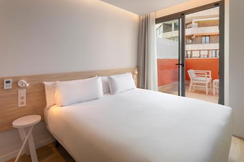 a bedroom with a large white bed and a balcony at B&B HOTEL Alicante Centro in Alicante