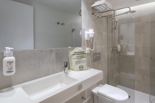 a bathroom with a sink and a toilet and a mirror at B&B HOTEL Alicante Centro in Alicante