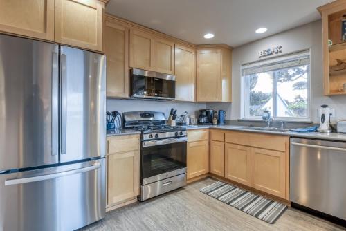 a kitchen with wooden cabinets and stainless steel appliances at Pacific Peek One - OceanView - EV Charger - Pet OK in Wecoma Beach