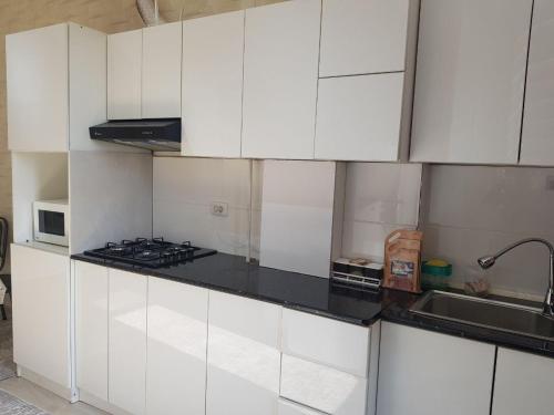 a kitchen with white cabinets and a stove top oven at Sukhrob PLS in Samarkand