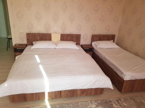 two beds in a small room with white sheets at Sukhrob PLS in Samarkand