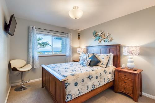 a bedroom with a bed and a window and a chair at Pacific Peek One - OceanView - EV Charger - Pet OK in Wecoma Beach