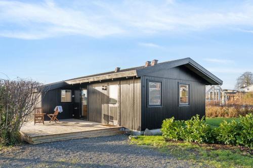a black tiny house with a wooden deck at Cozy Summer House Close To Beach And Nature in Rønde