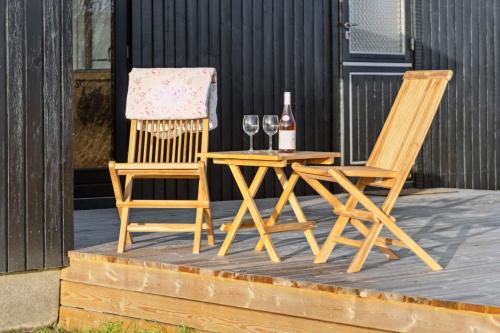 two chairs and a table with wine glasses on a deck at Cozy Summer House Close To Beach And Nature in Rønde