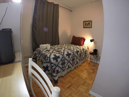 a small bedroom with a bed and a television at Saint Lawrence Residences and Suites in Toronto