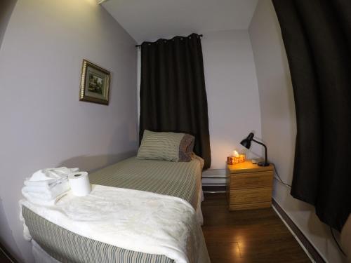 a small bedroom with a bed and a window at Saint Lawrence Residences and Suites in Toronto