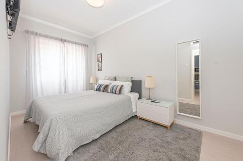 a white bedroom with a bed and a mirror at OrangeTreeHouses in Montijo