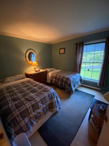 a bedroom with two beds and a mirror and a window at Paradise Eastern Township cottage in Cowansville