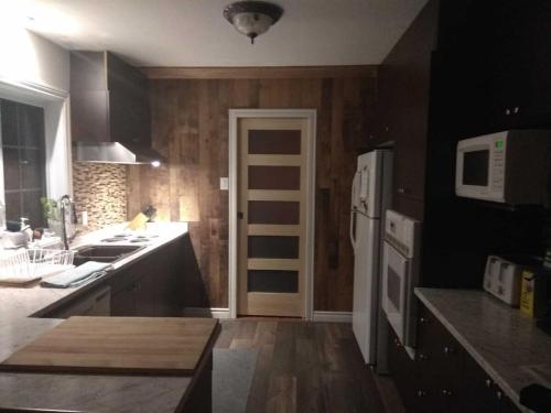 una cucina con pareti in legno e frigorifero bianco di Paradise Eastern Township cottage a Cowansville