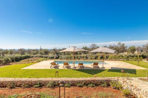 a garden with a pool and umbrellas at Villa del Cedro in Torre Vado