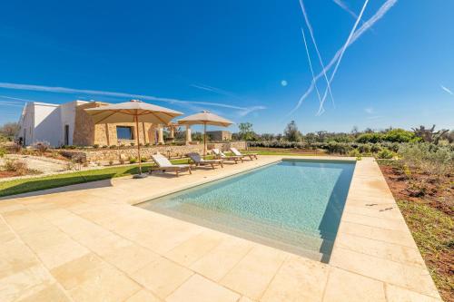 a pool with chairs and umbrellas next to a house at Villa del Cedro in Torre Vado