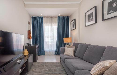 a living room with a gray couch and a television at OrangeTreeHouses in Montijo