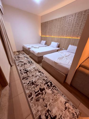 two beds in a hotel room with a rug at Locanda pyramids view in Cairo