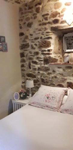 un lit dans une chambre avec un mur en pierre dans l'établissement Le Mas Joyeux - Gîte L'Orchidée en Cévennes, à Saint-Florent-sur-Auzonnet