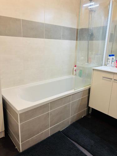 La salle de bains est pourvue d'une baignoire blanche à côté d'un comptoir. dans l'établissement Chambre spacieuse et lumineuse chez l habitant, à Angers