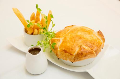 a plate with a pie and a bowl of vegetables at Lithgow Workies Club Motel in Lithgow