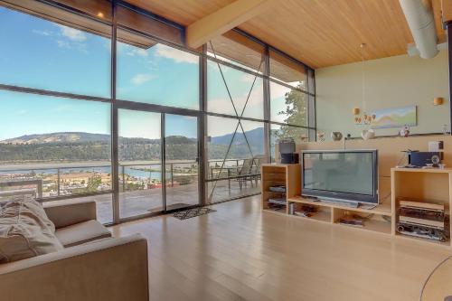 a living room with a television and large windows at Alizes 30 Day in Hood River