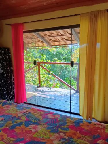 a bedroom with a window with a view of a deck at Chalé Aconchego in Santo Antônio do Leite