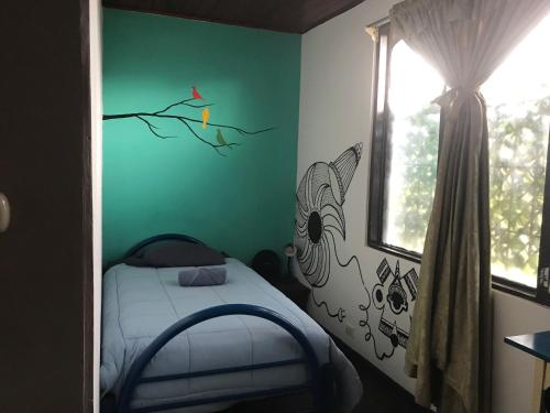 a bedroom with a bed with a bird on the wall at In the Wind Hostel and Guesthouse in San José