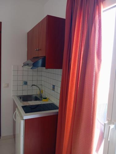 a small kitchen with red cabinets and a sink at ARTEMIS beach studios in Kalamaki Heraklion
