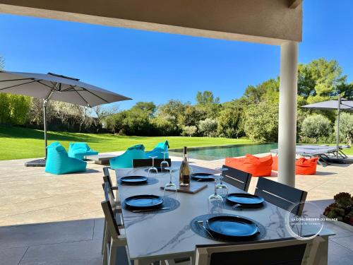 une table avec des chaises et un parasol sur une terrasse dans l'établissement Villa Maéna - Grande piscine - Entre mer et nature, à Carqueiranne