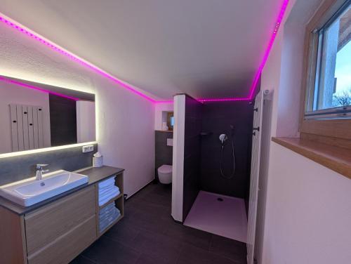 a bathroom with a sink and a toilet with pink lights at Ferienwohnung Goasnstoi - mit HotTub und Bergblick im Inntal in Flintsbach am Inn