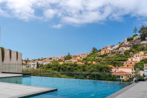 a view of a swimming pool with houses on a hill at Uptown II by An Island Apart in Funchal