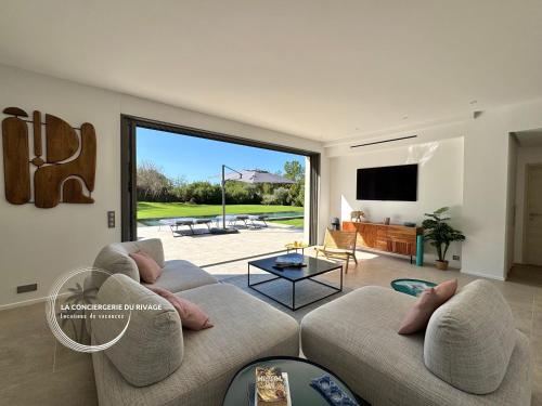 - un salon avec un canapé et une grande porte coulissante en verre dans l'établissement Villa Maéna - Grande piscine - Entre mer et nature, à Carqueiranne