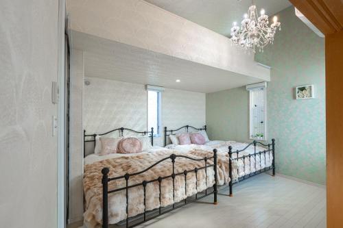 a bedroom with a bed with pink pillows and a chandelier at Papillon Paradis Nishi-Shinjuku in Tokyo