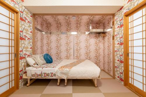 a small bedroom with a bed and floral wallpaper at Papillon Paradis Nishi-Shinjuku in Tokyo