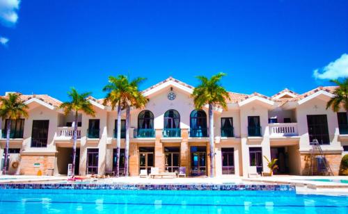 a building with palm trees in front of a swimming pool at Casa - Coastal Getaway Two-Bedroom Vacation Home with free parking in Amalfi by City de Mare in Cebu City