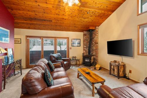 a living room with leather furniture and a flat screen tv at Cozy Ski-In Ski-Out Big Mountain Condo in Whitefish
