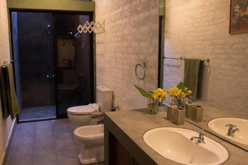 uma casa de banho com WC e um lavatório com flores no balcão em Neem Tree House em Kirinda