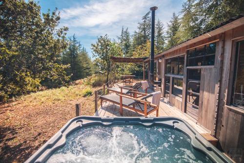 a hot tub on a deck next to a house at Domaine de la Vitarelle Glamping in Villanière