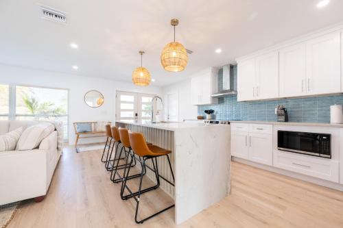 a kitchen with white cabinets and a bar with stools at Spacious 4BR Oasis with Pool Near Anna Maria Island in Bradenton