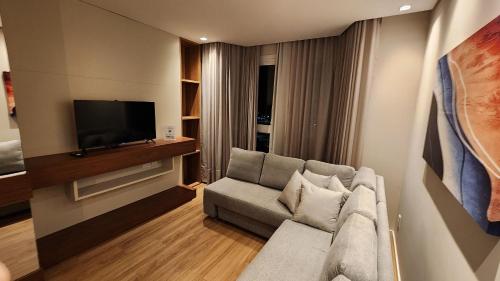 a living room with a couch and a flat screen tv at Deslumbrante Flat no Serra Class in Canela