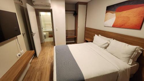 a bedroom with a bed and a flat screen tv at Deslumbrante Flat no Serra Class in Canela