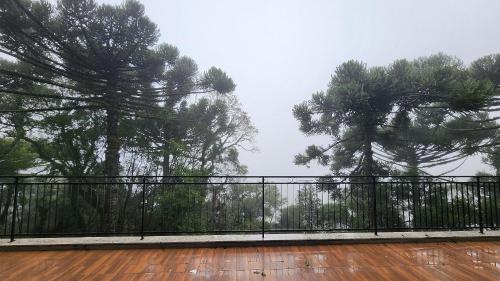 a balcony with trees and a deck with a fence at Deslumbrante Flat no Serra Class in Canela