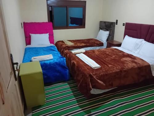 a hotel room with two beds and a mirror at Maison D'hôtes Chez Bassou Agoudal in Agoudal