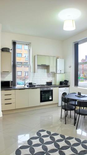 a kitchen with white cabinets and a table and chairs at Spacious 2 Bed Apart with Patio in Camden WR201 in London