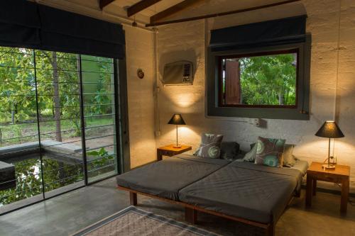 a bedroom with a bed and a large window at Neem Tree House in Kirinda