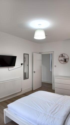 a white bedroom with a bed and a flat screen tv at Duplex 3 Bed Apt with patio in Camden WR202 in London