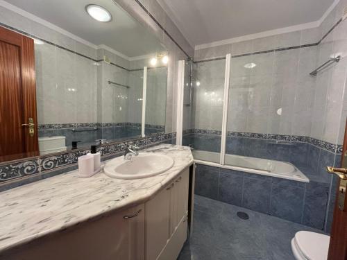 a bathroom with a sink and a tub and a mirror at Povoa Center Beach Apartment in Póvoa de Varzim