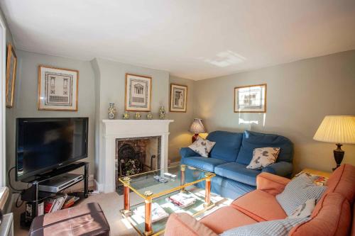 a living room with a blue couch and a tv at IVY COTTAGE in Pulborough