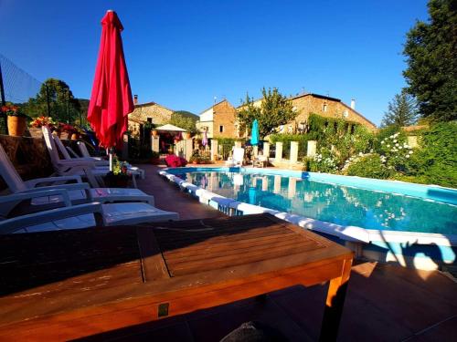 - une piscine avec des chaises et un parasol rouge dans l'établissement Le Mas Joyeux - Gîte L'Orchidée en Cévennes, à Saint-Florent-sur-Auzonnet