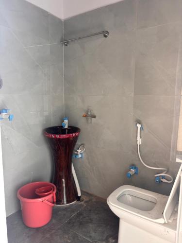 a bathroom with a toilet and a sink and a bucket at Radha Madhavam Luxurious Boutique Stay in Mathura
